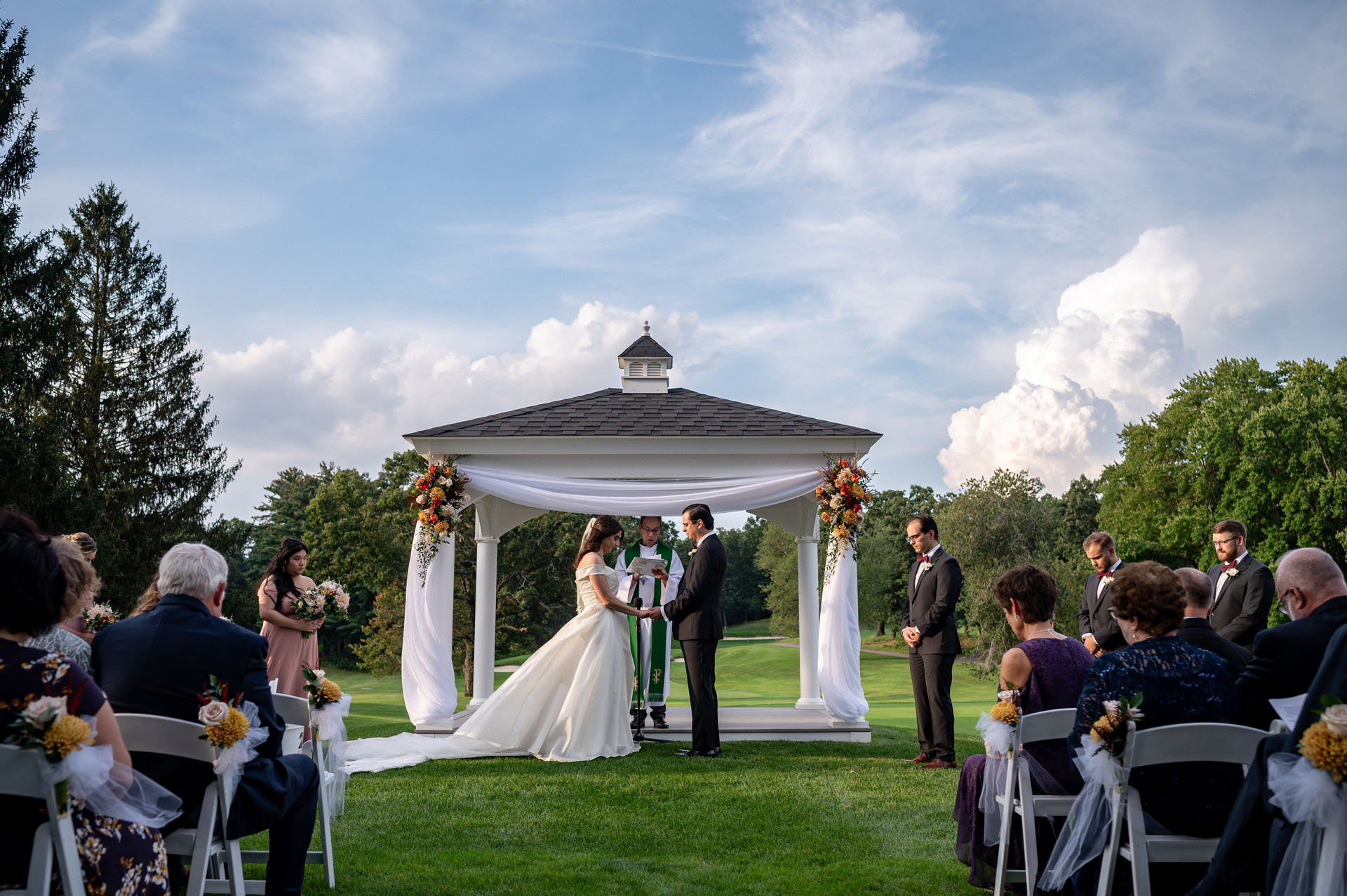 Gorgeous outdoor wedding ceremony, medium view with picturesque clouds